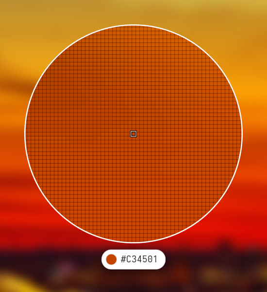 The color picker lens over an orange sky, with a pixel grid, a small square on the pixel under the pointer, and a pill below showing the color and its value #C34501